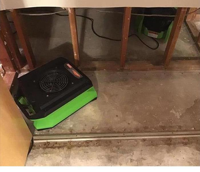 bare floor with SERVPRO green air mover on it helping to dry things up