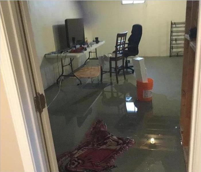 A room with significant water damage and several inches of water on the carpeted floor